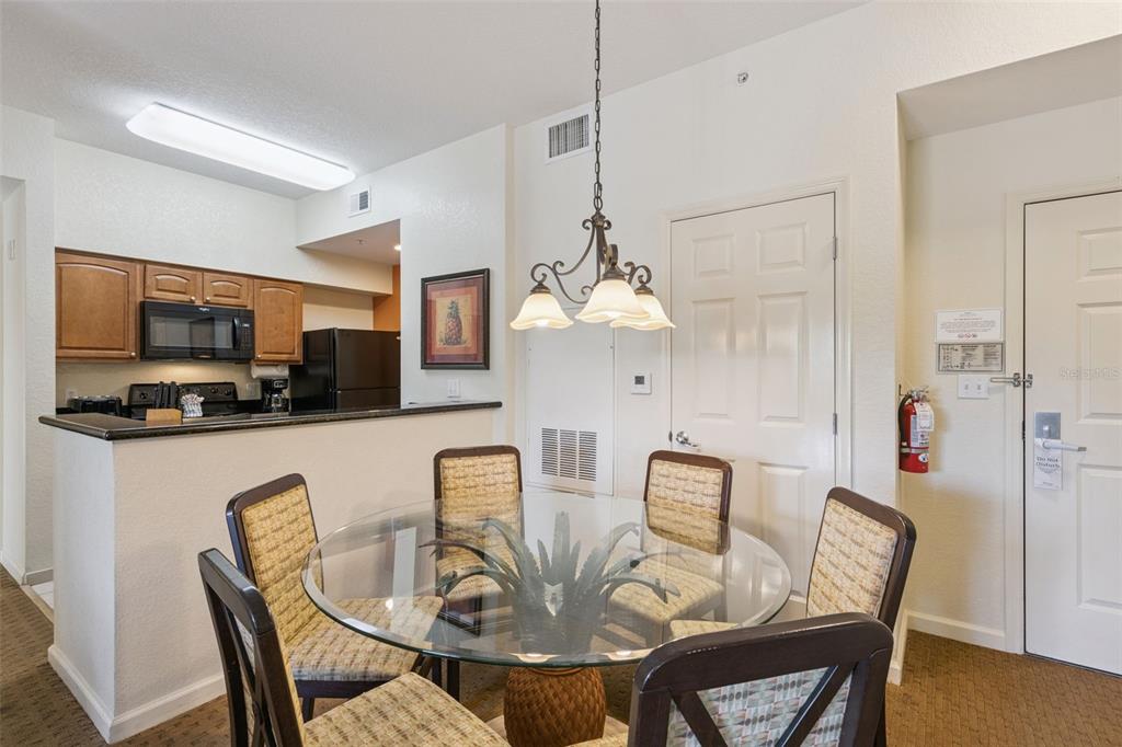 A dining area with a glass table and four chairs sits next to a kitchen — 8112 POINCIANA BOULEVARD UNIT 1202, ORLANDO, FL