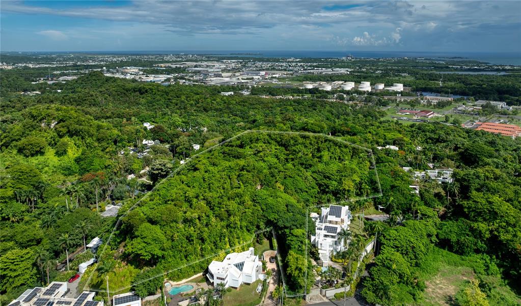 An aerial view shows two modern white houses nestled within a dense, forested hillside area — Lot E 502 TINTILLO STREET, GUAYNABO, PR
