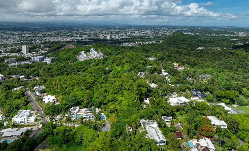 An aerial view shows a hillside residential area surrounded by dense forest and urban sprawl — Lot E 502 TINTILLO STREET, GUAYNABO, PR