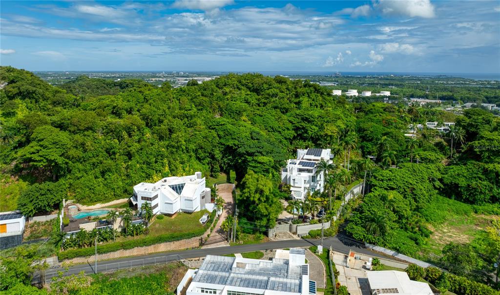 An aerial view shows several modern white houses nestled within a lush, green hillside landscape — Lot E 502 TINTILLO STREET, GUAYNABO, PR