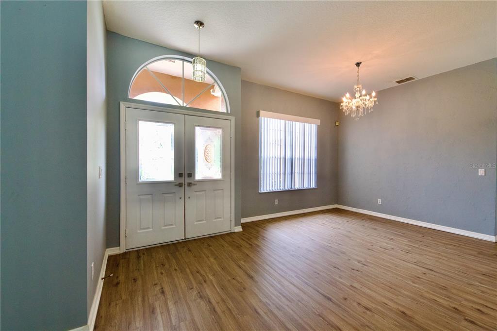 An entryway with wood-look flooring, a double front door, and a crystal chandelier — 13808 RUDI LOOP, SPRING HILL, FL