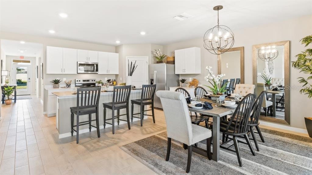 An open-concept kitchen and dining area features white cabinets, a breakfast bar, and tile flooring — 4912 TUSCOLA BOULEVARD, NORTH PORT, FL