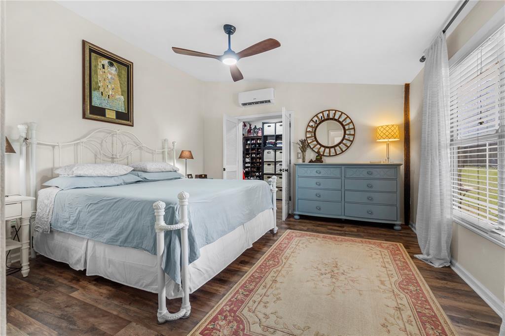 A bedroom features a white iron bed, a blue dresser, a rug, and a ceiling fan — 7650 NE 40TH STREET, HIGH SPRINGS, FL