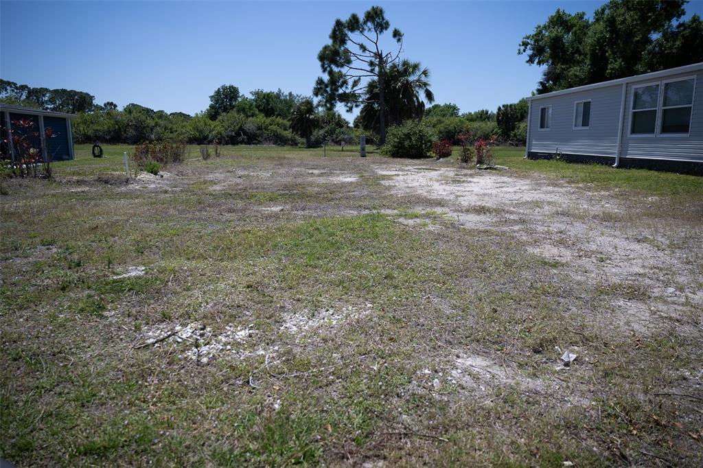 A grassy, sandy lot sits between a small shed and a light-colored mobile home — 307 ROBALO, NORTH PORT, FL