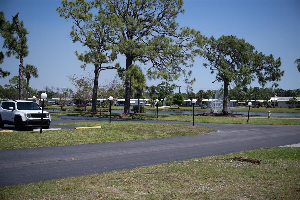 A white SUV is parked on a paved road near a pond with a water fountain — 307 ROBALO, NORTH PORT, FL