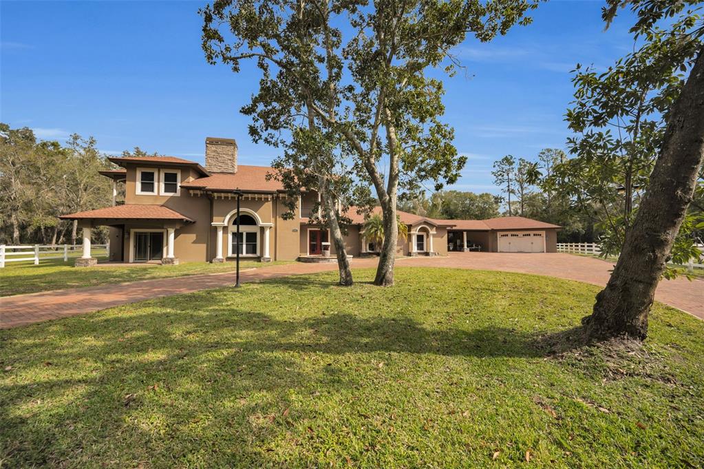 A two-story tan house with a brick driveway, a chimney, and an attached garage — 249 DOGWOOD TRACE, TARPON SPRINGS, FL