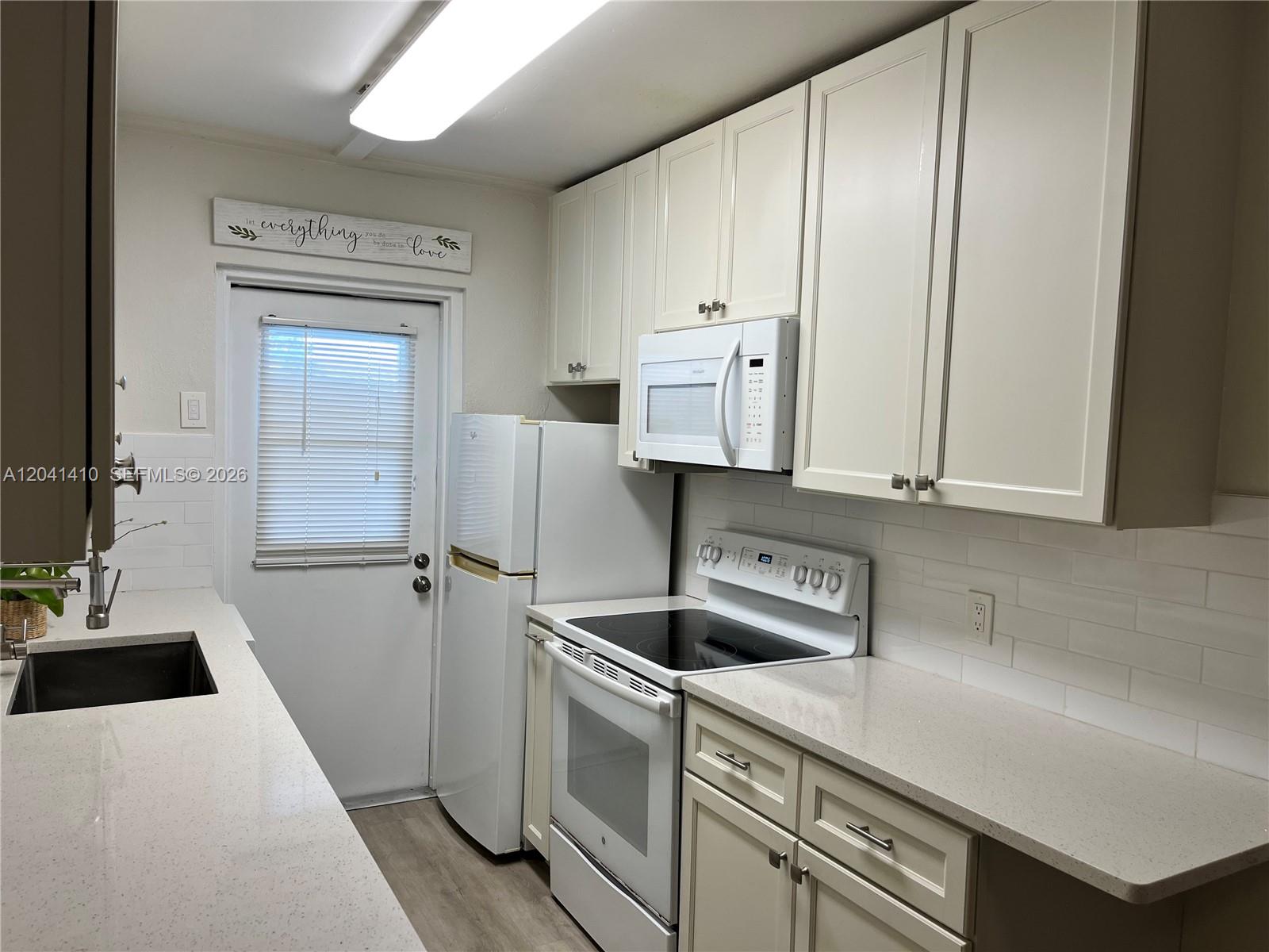 A kitchen features white cabinetry, quartz countertops, a white stove, and a white refrigerator — 6550 Royal Palm Blvd # 105A, Margate FL 33063, MARGATE, FL