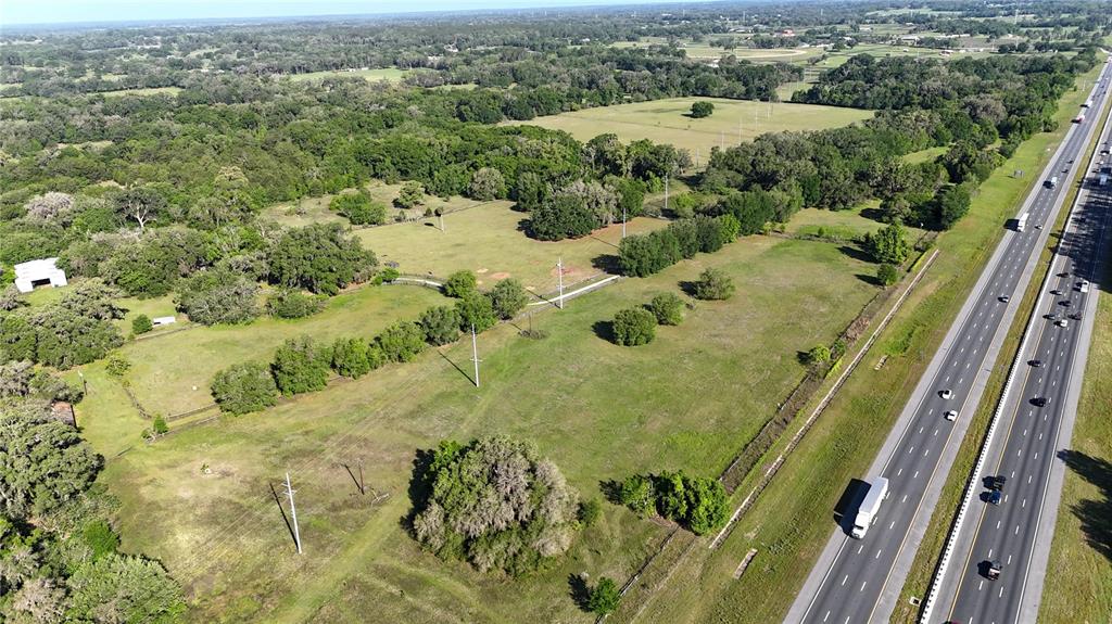 An aerial view shows a large, grassy lot adjacent to a multi-lane highway — 9126 NW 49TH AVENUE ROAD, OCALA, FL