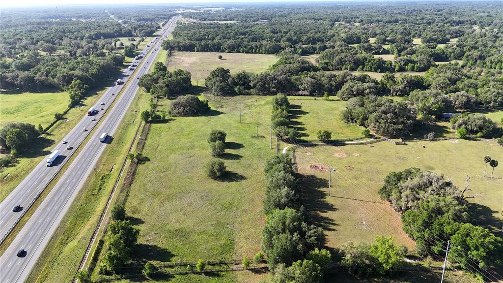 An aerial view shows a large, grassy plot of land adjacent to a multi-lane highway — 9126 NW 49TH AVENUE ROAD, OCALA, FL