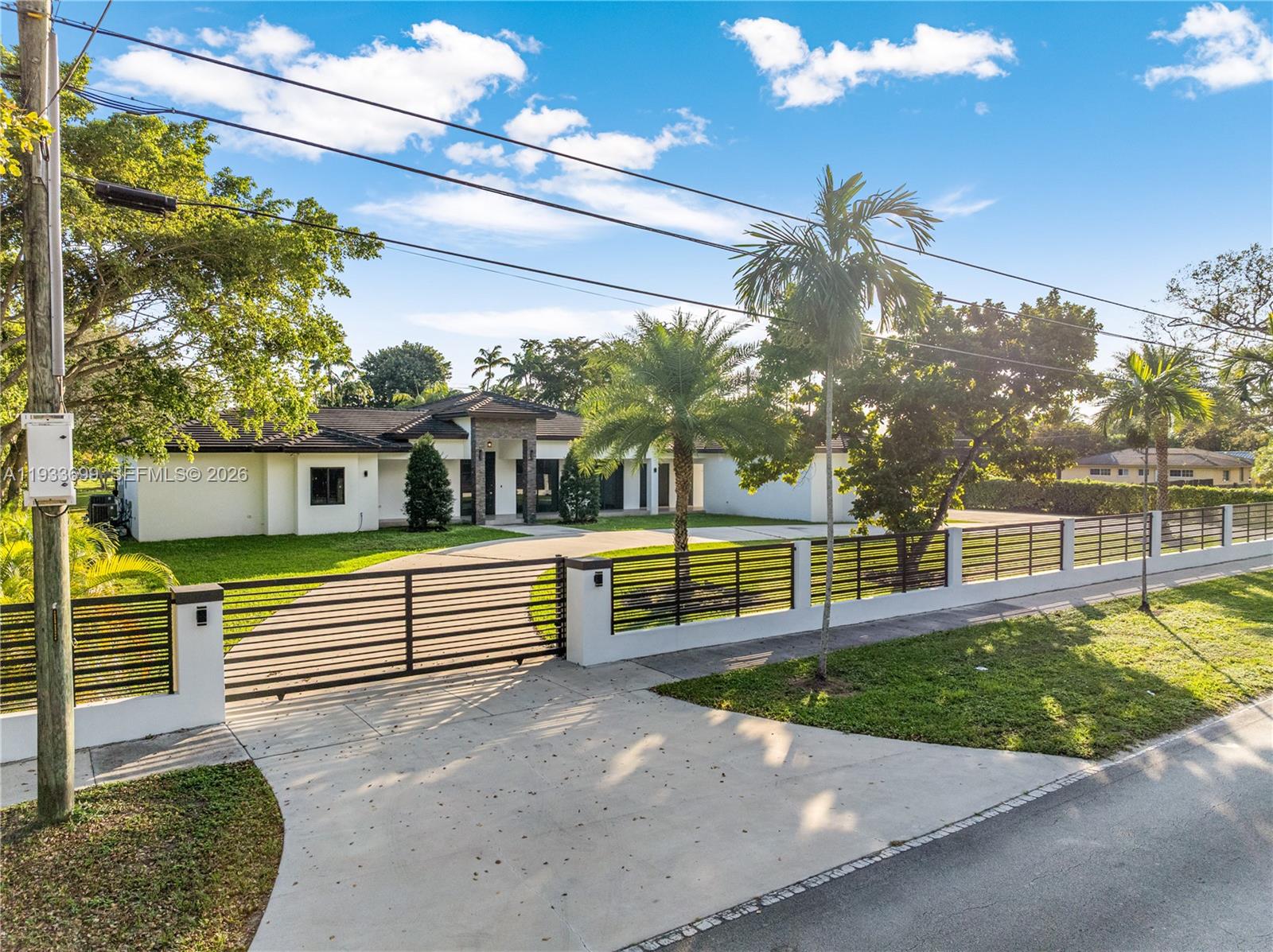 A single-story white house with a dark roof sits behind a gated concrete driveway — 10398 SW 64th St, Miami FL 33173, MIAMI, FL