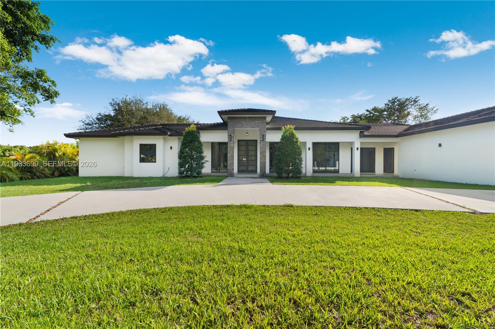 A single-story house with a stone-accented entryway and a large concrete driveway — 10398 SW 64th St, Miami FL 33173, MIAMI, FL