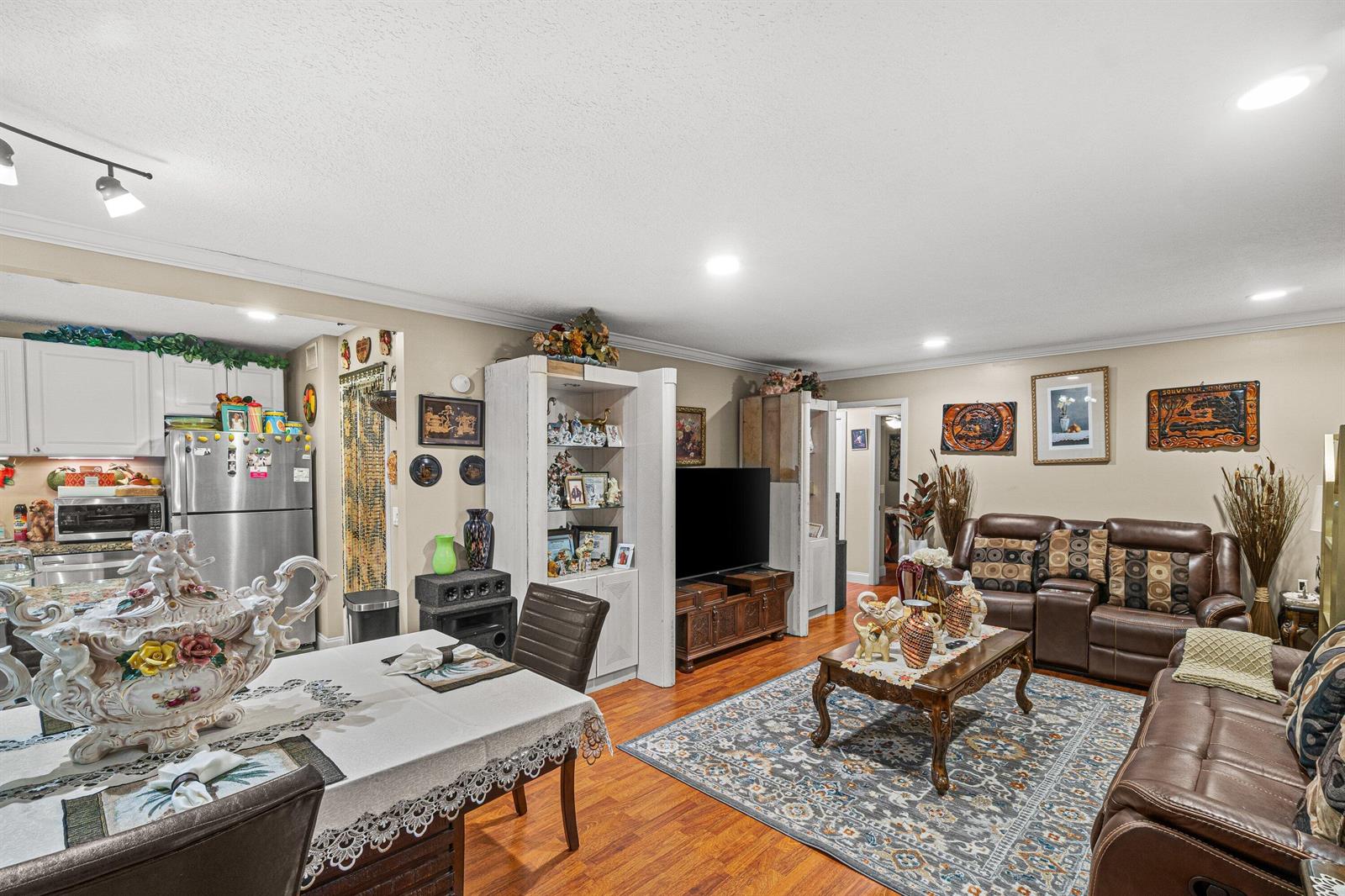 An open-concept living and dining area features wood-look flooring, leather furniture, and a kitchen — 526 Shady Pine Way # D2, FL 33415, FL