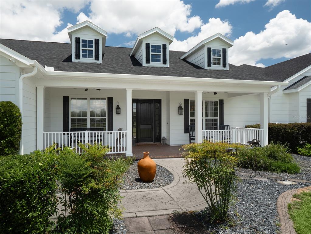 A white house with a covered front porch, three dormer windows, and a landscaped yard — 4985 SW 85TH STREET, OCALA, FL