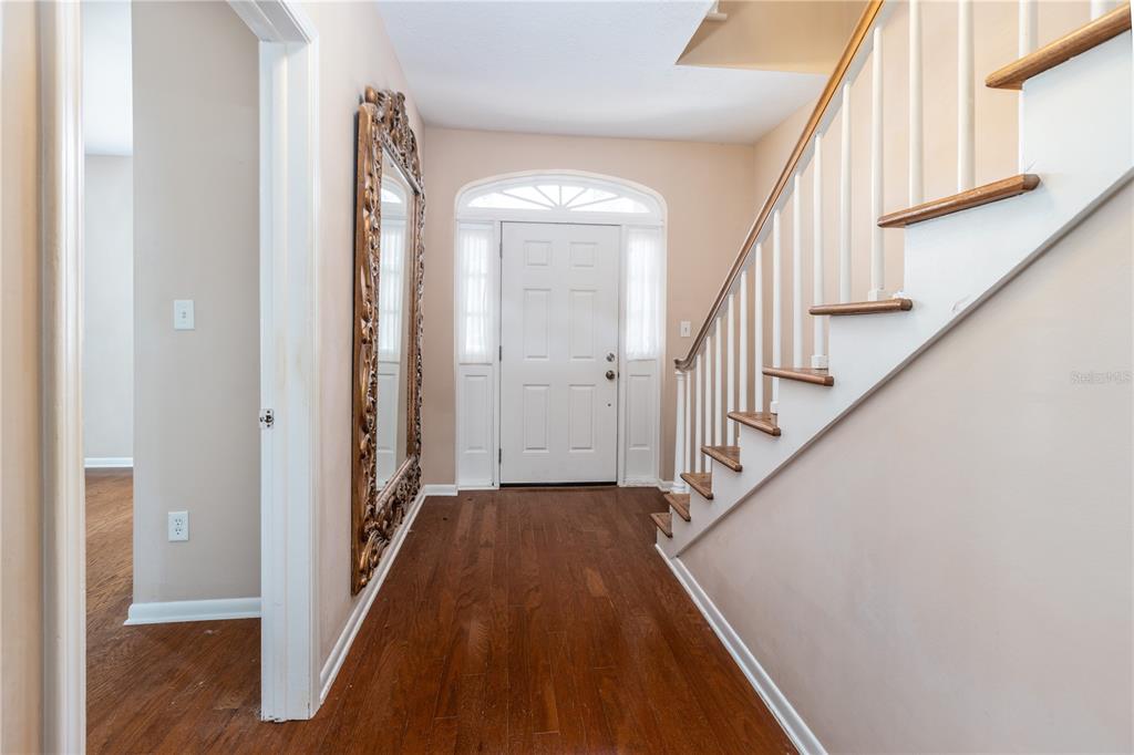 An entryway features hardwood floors, a staircase with white railings, and a large ornate mirror — 9252 SAN JOSE BOULEVARD UNIT 1802, JACKSONVILLE, FL