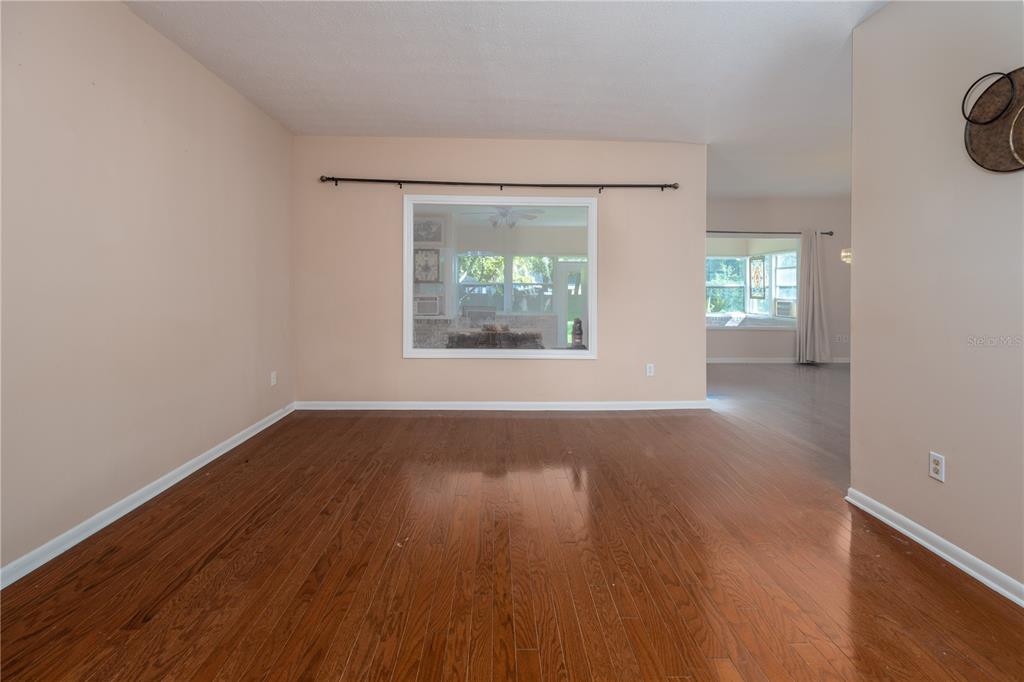An empty room with hardwood floors, a large pass-through window, and light-colored walls — 9252 SAN JOSE BOULEVARD UNIT 1802, JACKSONVILLE, FL