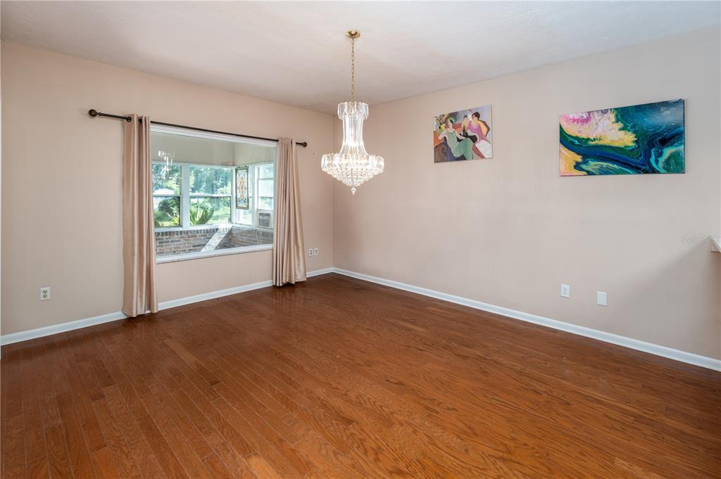 An empty dining room features hardwood floors, a crystal chandelier, and two pieces of wall art — 9252 SAN JOSE BOULEVARD UNIT 1802, JACKSONVILLE, FL