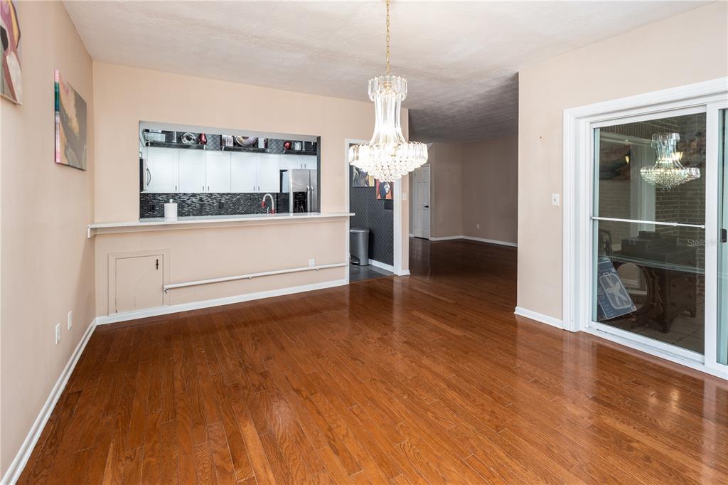 A dining room with hardwood floors, a crystal chandelier, and a pass-through to the kitchen — 9252 SAN JOSE BOULEVARD UNIT 1802, JACKSONVILLE, FL