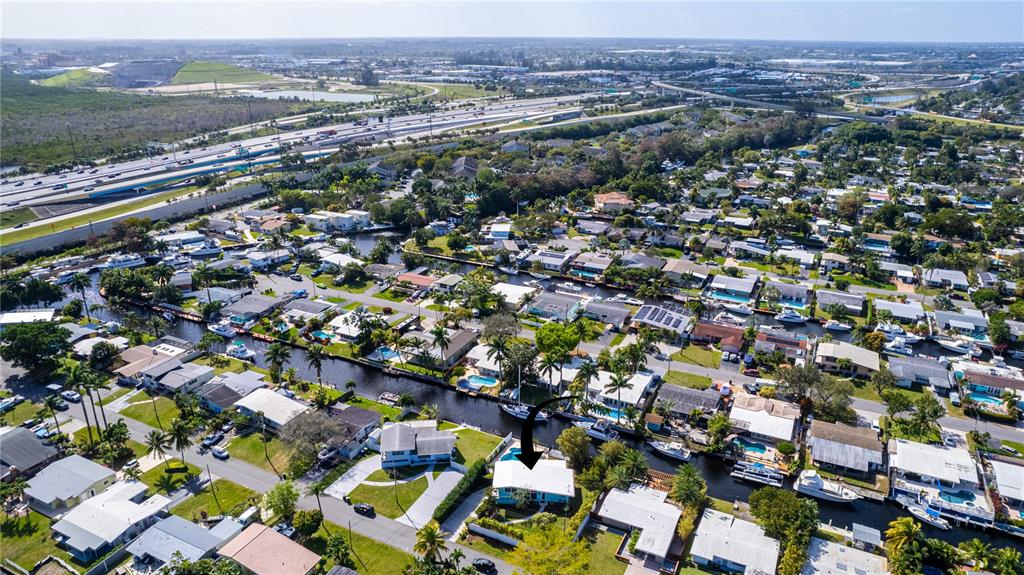An aerial view shows a residential neighborhood with houses along a canal near a highway — 2631 KEY LARGO LANE, FORT LAUDERDALE, FL