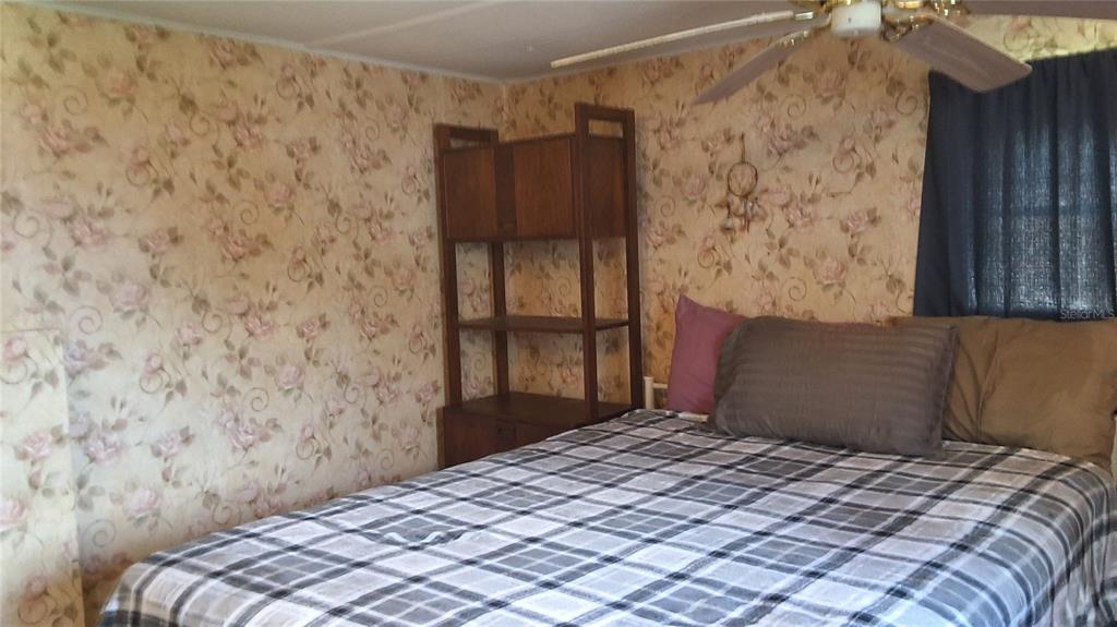 A bedroom features floral wallpaper, a plaid bedspread, and a wooden shelving unit — 2488 N PARK POINT, HERNANDO, FL