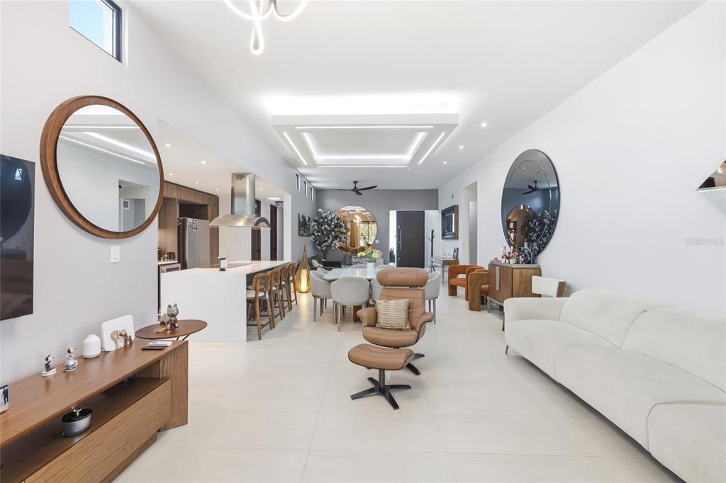 An open-concept living and dining area features white tile floors, modern lighting, and neutral furniture — Urb Las Casonas ARANDA, GUAYNABO, PR