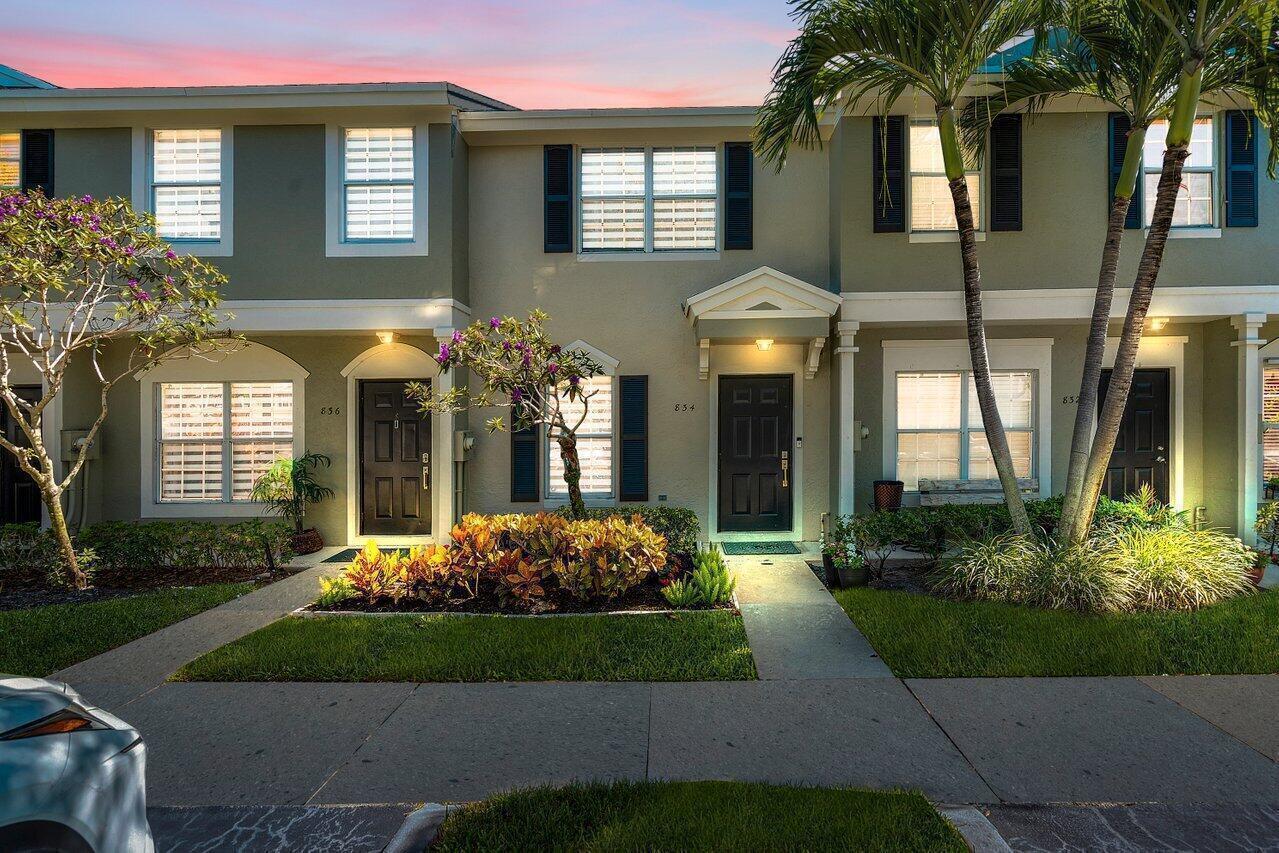A two-story townhouse exterior with a green facade, dark doors, and a landscaped front yard — 834 Kokomo Key Lane, Delray Beach FL 33483, DELRAY BEACH, FL
