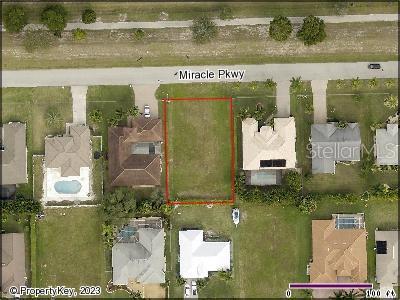 An aerial view shows a vacant rectangular lot outlined in red situated between two houses — 2510 MIRACLE PARKWAY, CAPE CORAL, FL