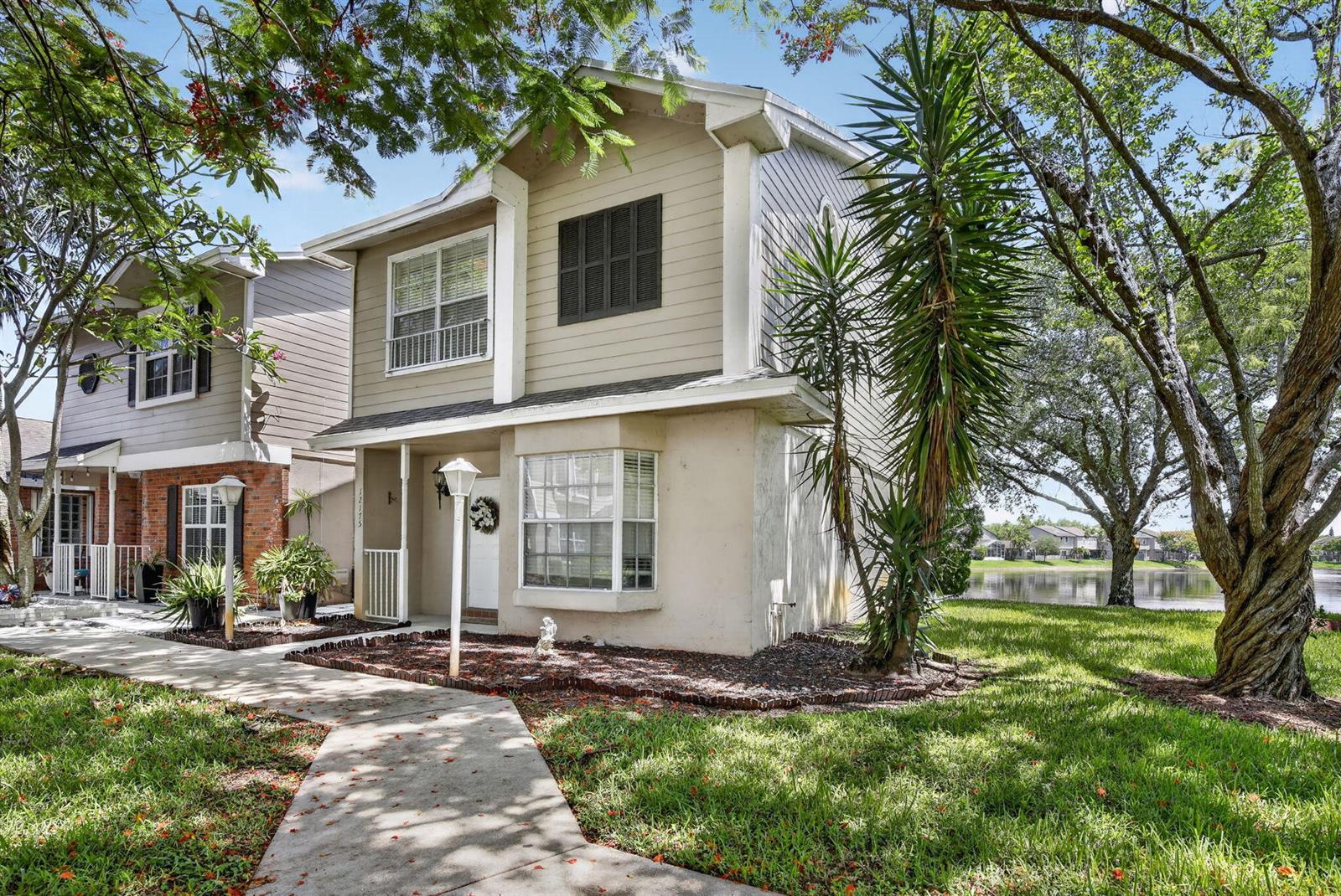 A two-story beige house with a front walkway, bay window, and a lake in back — 12175 NW 36th Place, Sunrise FL 33323, SUNRISE, FL