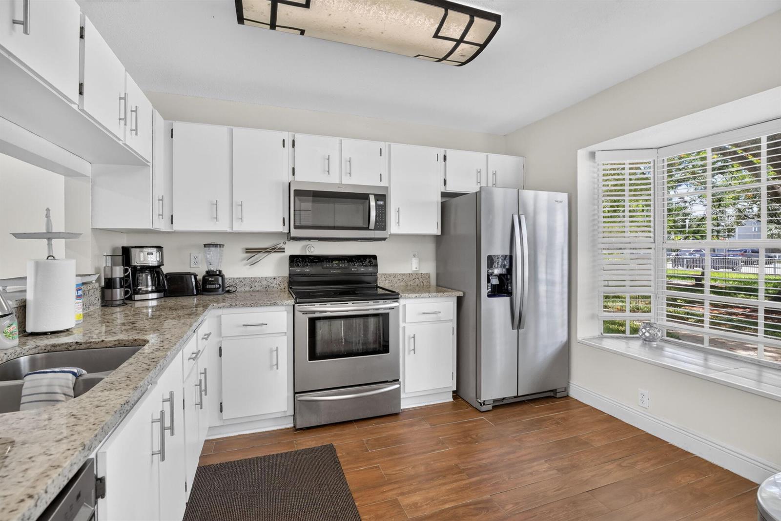 A kitchen with white cabinets, granite countertops, stainless steel appliances, and a bay window — 12175 NW 36th Place, Sunrise FL 33323, SUNRISE, FL