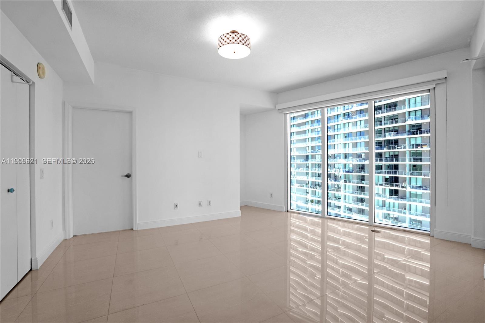 An empty room features white walls, tile flooring, a ceiling light, and floor-to-ceiling windows — 60 SW 13th St # 1700, Miami FL 33130, MIAMI, FL