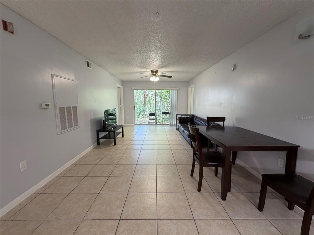 A living and dining room area features tile flooring, a ceiling fan, and sliding doors — 3921 SW 34TH STREET UNIT 301, GAINESVILLE, FL