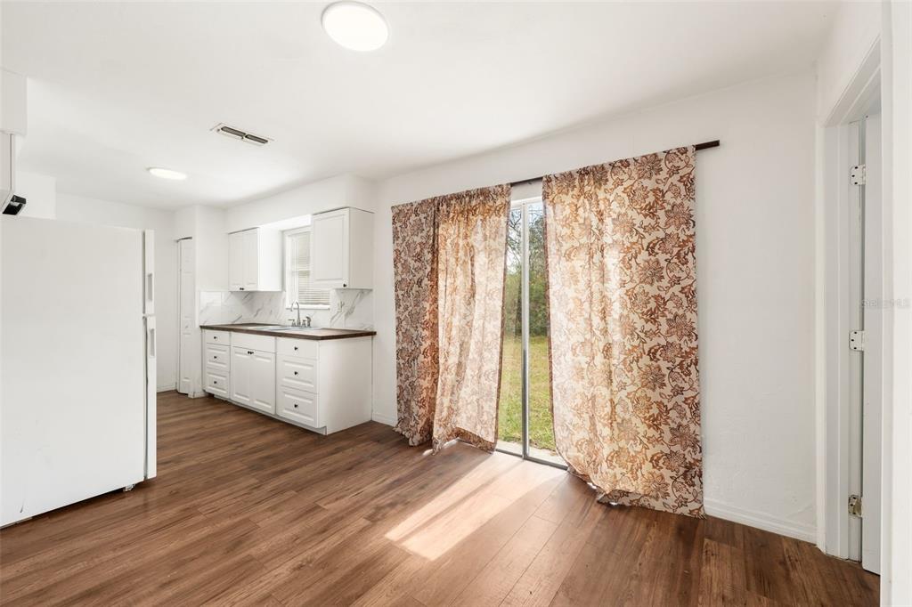 A kitchen with white cabinets and wood-look flooring opens to a patio through sliding doors — 1911 SE 14TH AVENUE, GAINESVILLE, FL