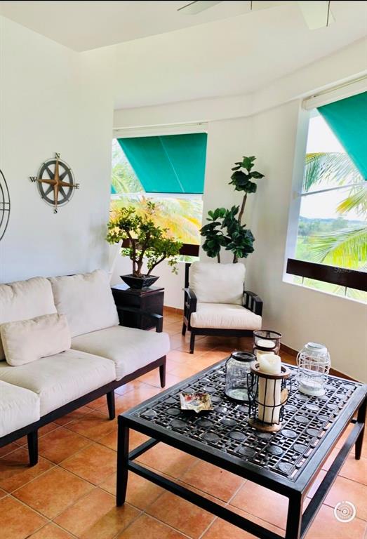 A sunroom features a white sofa, an armchair, a coffee table, and large windows — 802 RIO MAR VILLAGE, RIO GRANDE, PR
