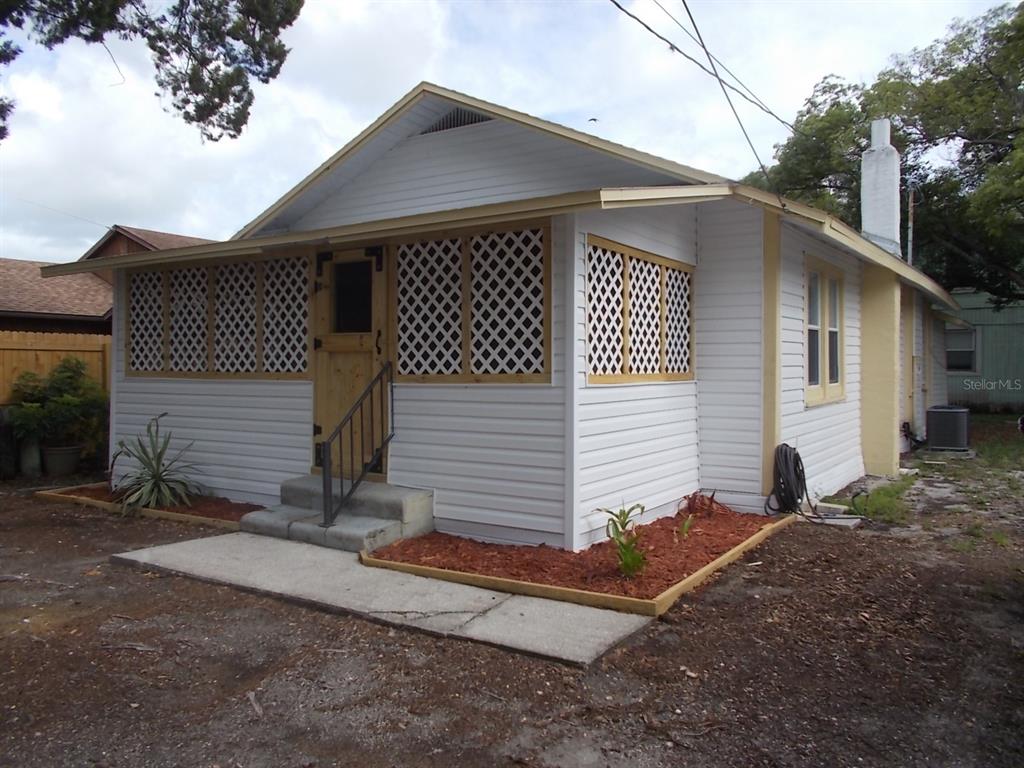 A white house with a lattice-enclosed front porch, a wooden door, and a concrete walkway — 518 6TH AVENUE SW, LARGO, FL