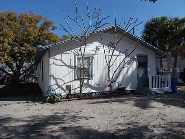 A white, single-story house with vertical siding and a small front porch under a clear sky — 518 6TH AVENUE SW, LARGO, FL