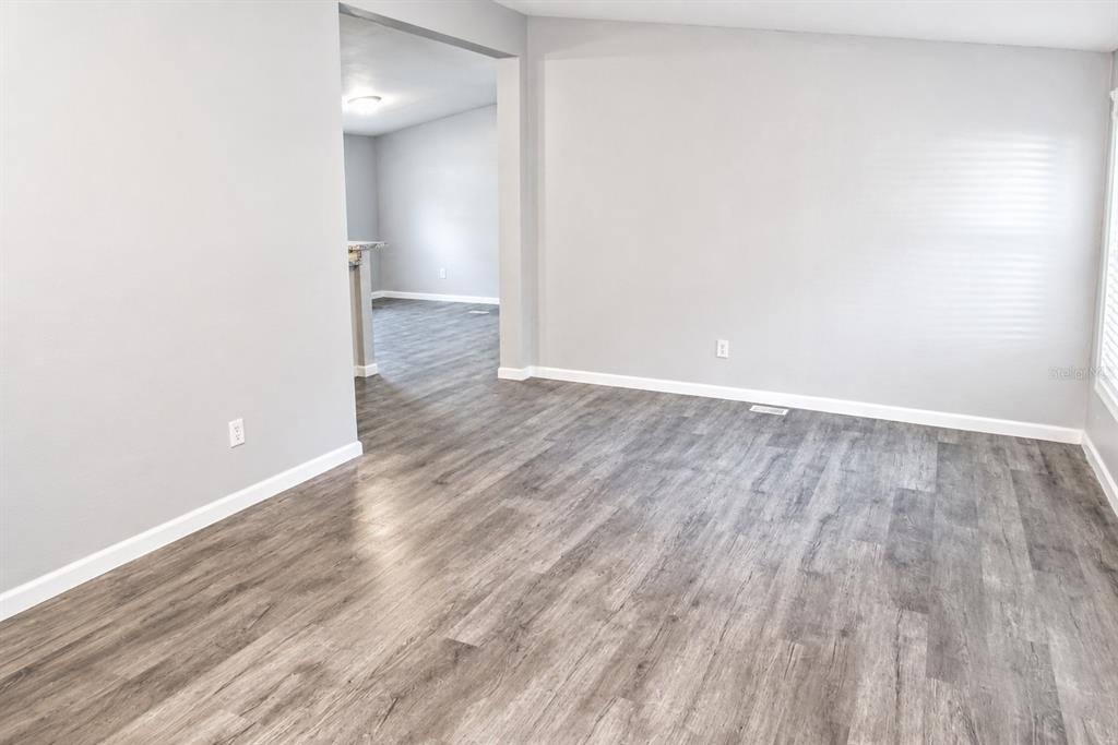 An empty room with light gray walls and wood-look vinyl plank flooring — 4517 LA FORCE STREET, ZEPHYRHILLS, FL
