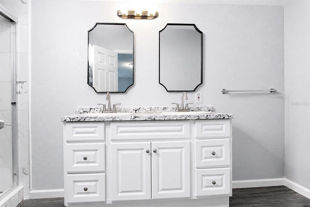 A bathroom vanity with two sinks, mirrors, and white cabinets against a gray wall — 4517 LA FORCE STREET, ZEPHYRHILLS, FL