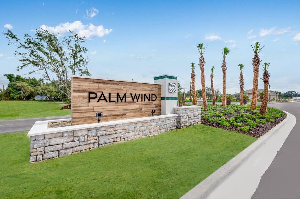 A stone and wood monument sign for Palm Wind stands on a grassy lawn — 13747 SQUALL LANE, HUDSON, FL