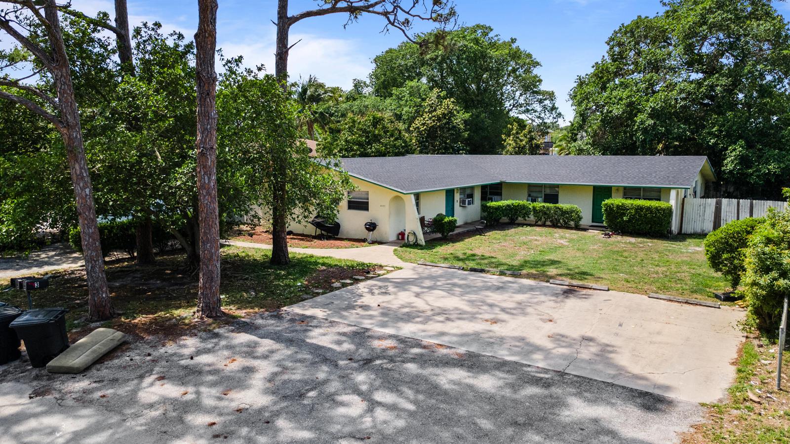 An exterior view of a single-story house with a concrete driveway and surrounding trees — 4453 Stevens Road, FL 33461, FL