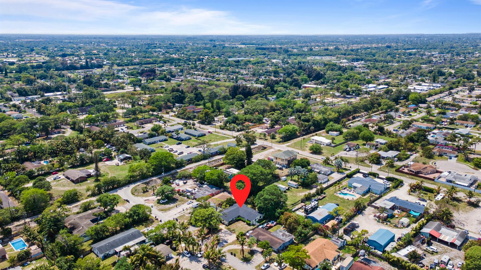 An aerial view shows a residential house marked with a red pin among trees — 4453 Stevens Road, FL 33461, FL