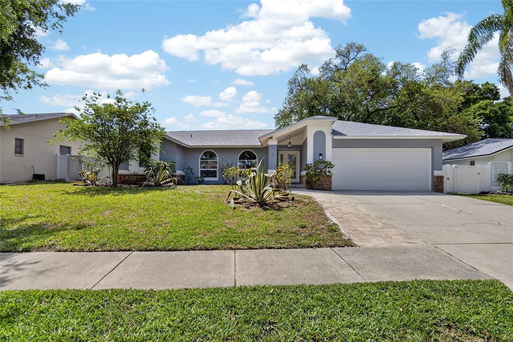 A single-story house with a gray exterior, a two-car garage, and a front lawn — 1668 ALLENS RIDGE DRIVE N, PALM HARBOR, FL