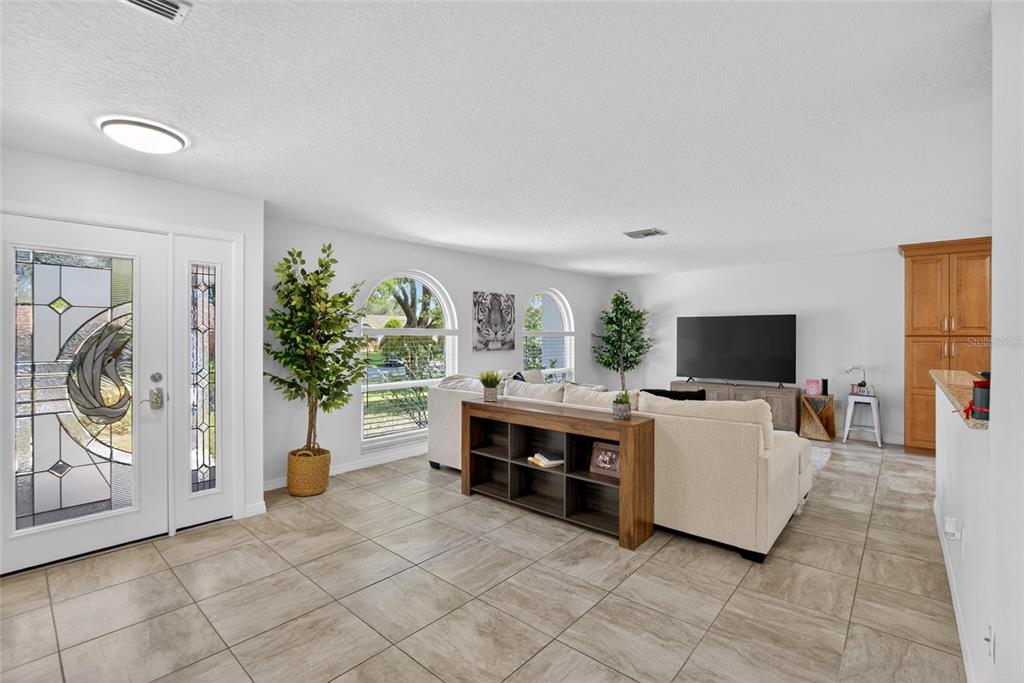 A living room features light tile flooring, a white sofa, and arched windows near the entrance — 1668 ALLENS RIDGE DRIVE N, PALM HARBOR, FL