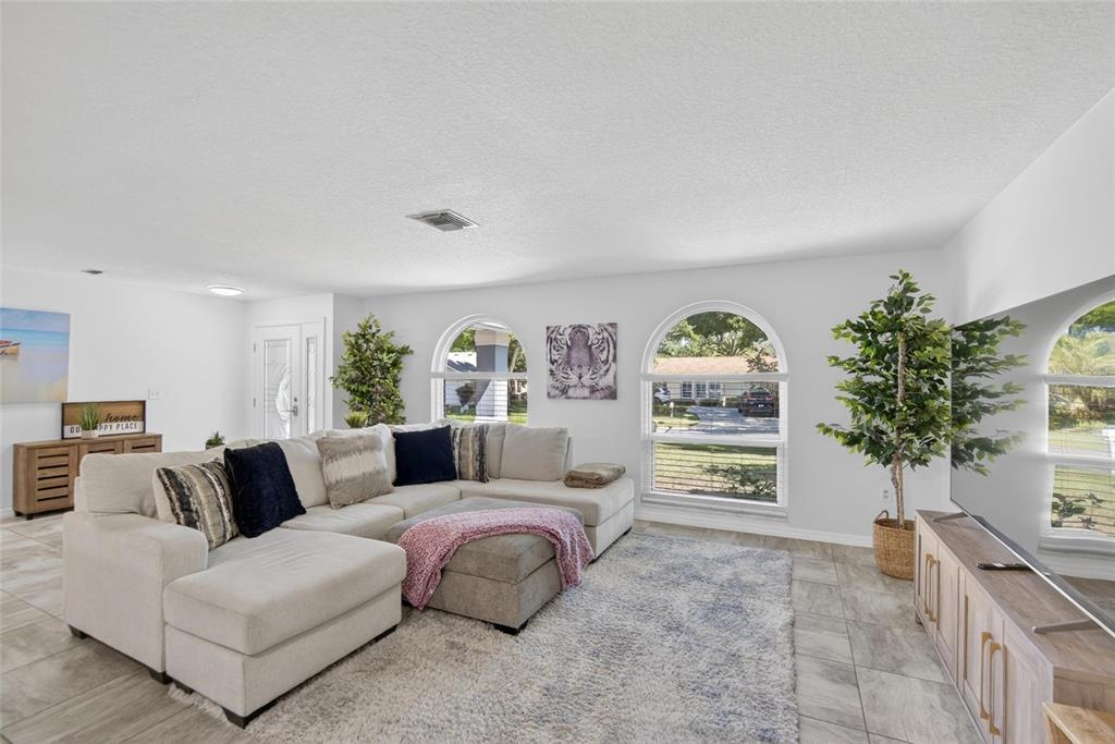 A living room features a large sectional sofa, tiled floors, and two arched windows — 1668 ALLENS RIDGE DRIVE N, PALM HARBOR, FL