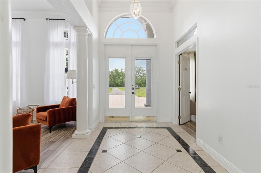 A bright entryway features white walls, tile flooring with a dark border, and double glass doors — 4529 CAESAR AVENUE, ORLANDO, FL