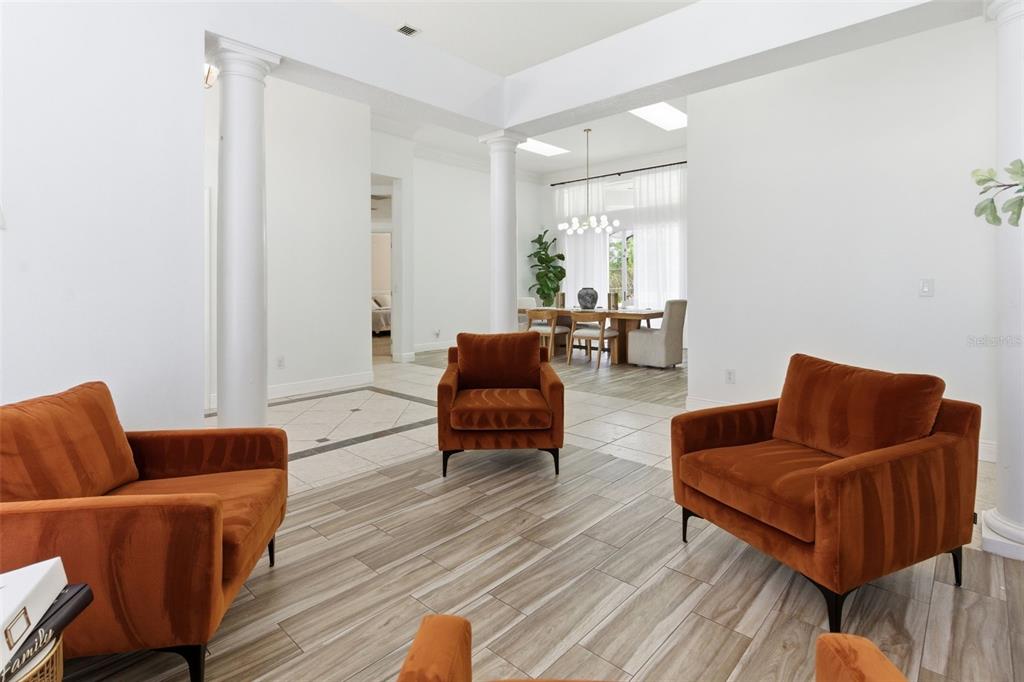 A bright, open-concept living area features three orange velvet armchairs on wood-look tile floors — 4529 CAESAR AVENUE, ORLANDO, FL