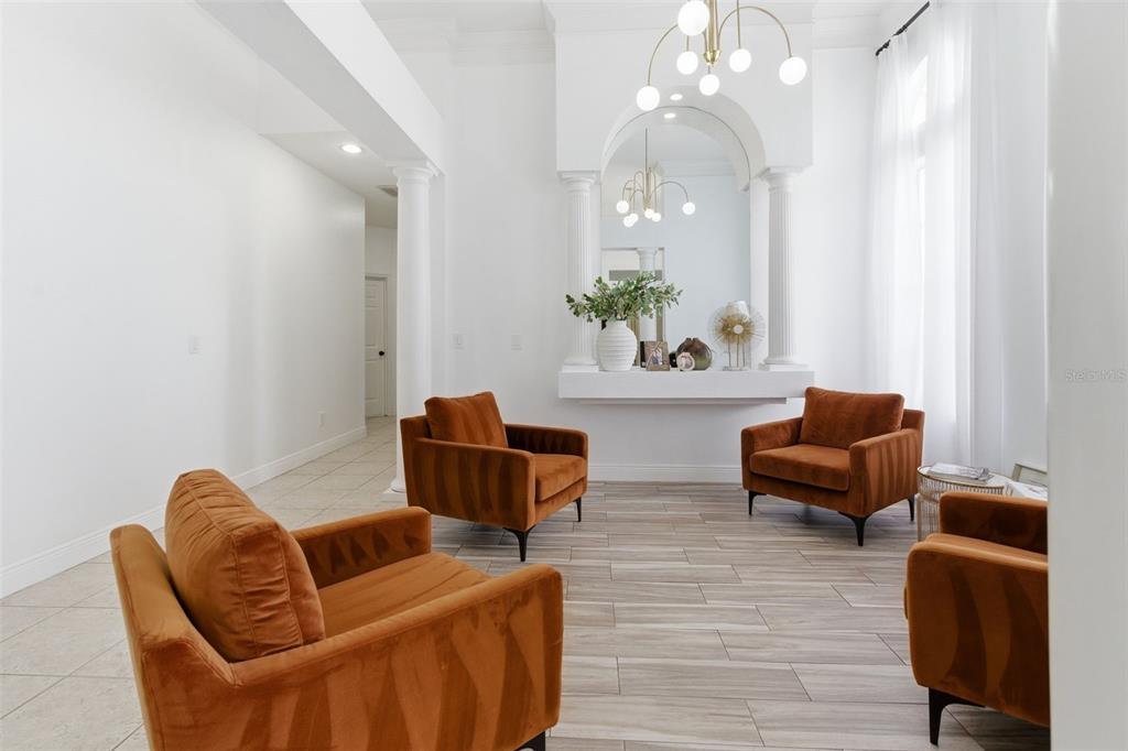 A bright, white living room features four rust-colored armchairs, a decorative arched niche, and tile flooring — 4529 CAESAR AVENUE, ORLANDO, FL