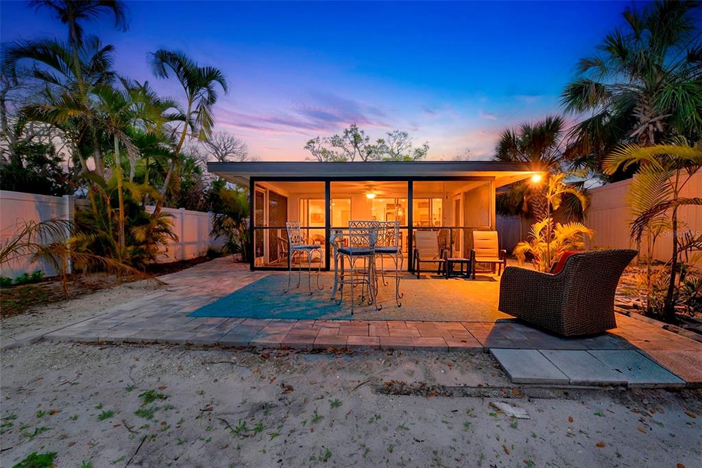 A patio with a screened-in porch, outdoor furniture, and palm trees at twilight — 8456 MIDNIGHT PASS ROAD, SARASOTA, FL
