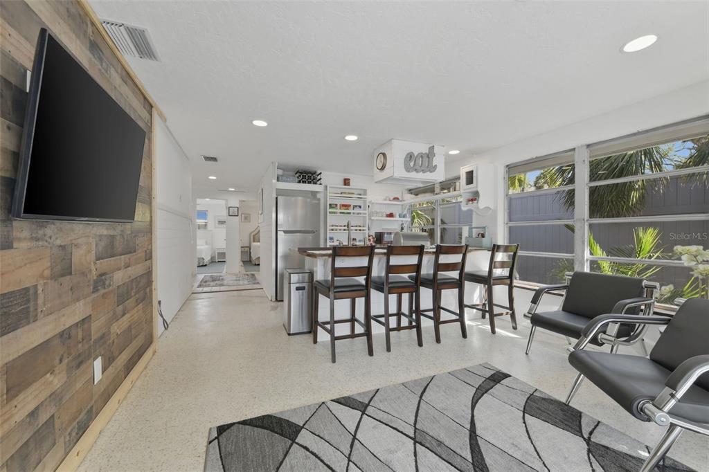 A kitchen with a breakfast bar and stools opens into a living area with wood-paneled walls — 8456 MIDNIGHT PASS ROAD, SARASOTA, FL