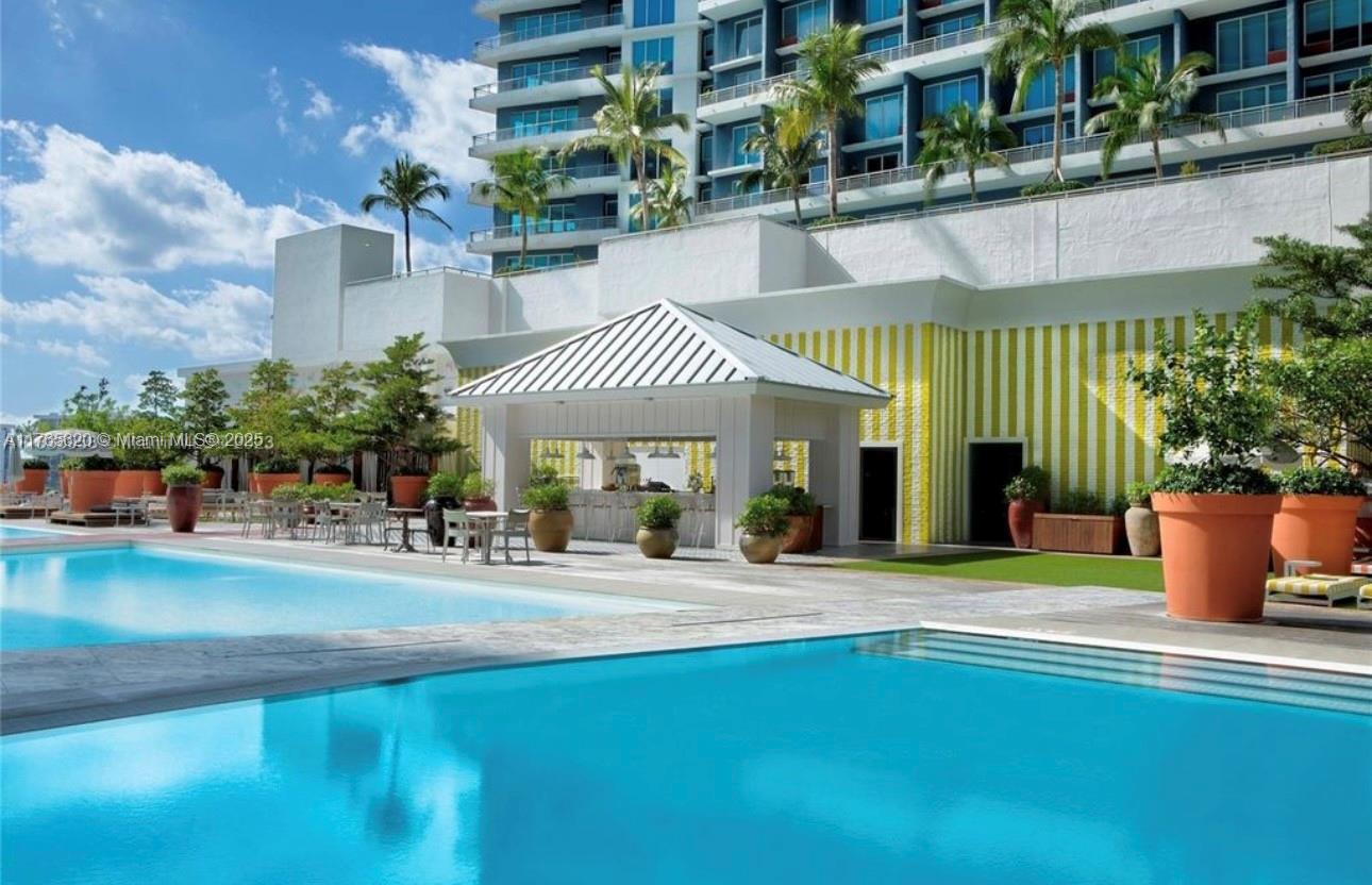 A swimming pool sits in front of a poolside bar and a modern apartment building — 1300 S Miami Ave # 3108, Miami FL 33130, MIAMI, FL