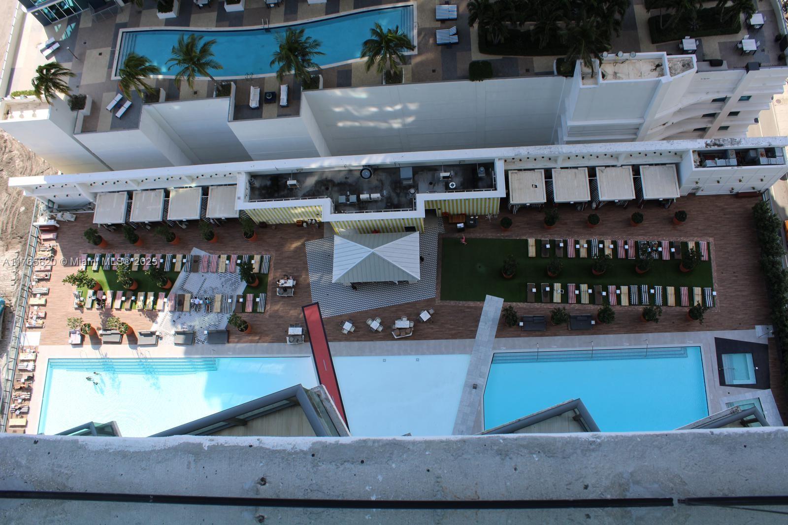 An aerial view shows a hotel pool deck with lounge chairs, cabanas, and two swimming pools — 1300 S Miami Ave # 3108, Miami FL 33130, MIAMI, FL