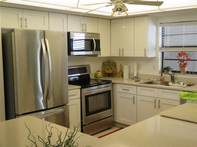 A kitchen featuring white cabinets, stainless steel appliances, and a ceiling fan — 1400 1ST AVENUE W UNIT 504, BRADENTON, FL